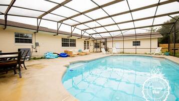 Uma área de piscina ao ar livre coberta, com espreguiçadeiras e uma mesa.
