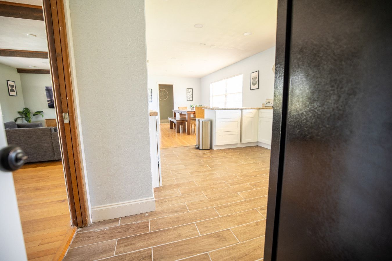 A modern kitchen with white cabinets, a dining area with a table and chairs, and a wooden floor.