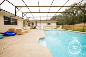 A covered outdoor swimming pool area with lounge chairs and a wooden fence. - Winter Park Charmer - Heated Pool Home - Close to everything (Winter Park)