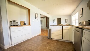 A modern kitchen with white cabinetry, a wooden countertop, and a stainless steel dishwasher. - Winter Park Charmer - Heated Pool Home - Close to everything (Winter Park)