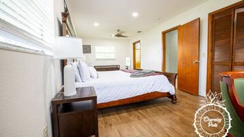 Um quarto com uma cama de madeira, mesa de cabeceira, luminária e uma cadeira.