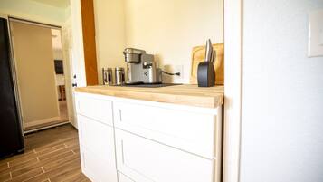 A kitchen with white cabinets, a wooden countertop, a coffee maker, and a toaster.