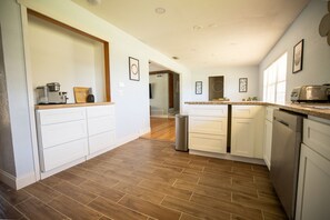 Una cocina moderna con armarios blancos, encimera de madera y lavavajillas de acero inoxidable.