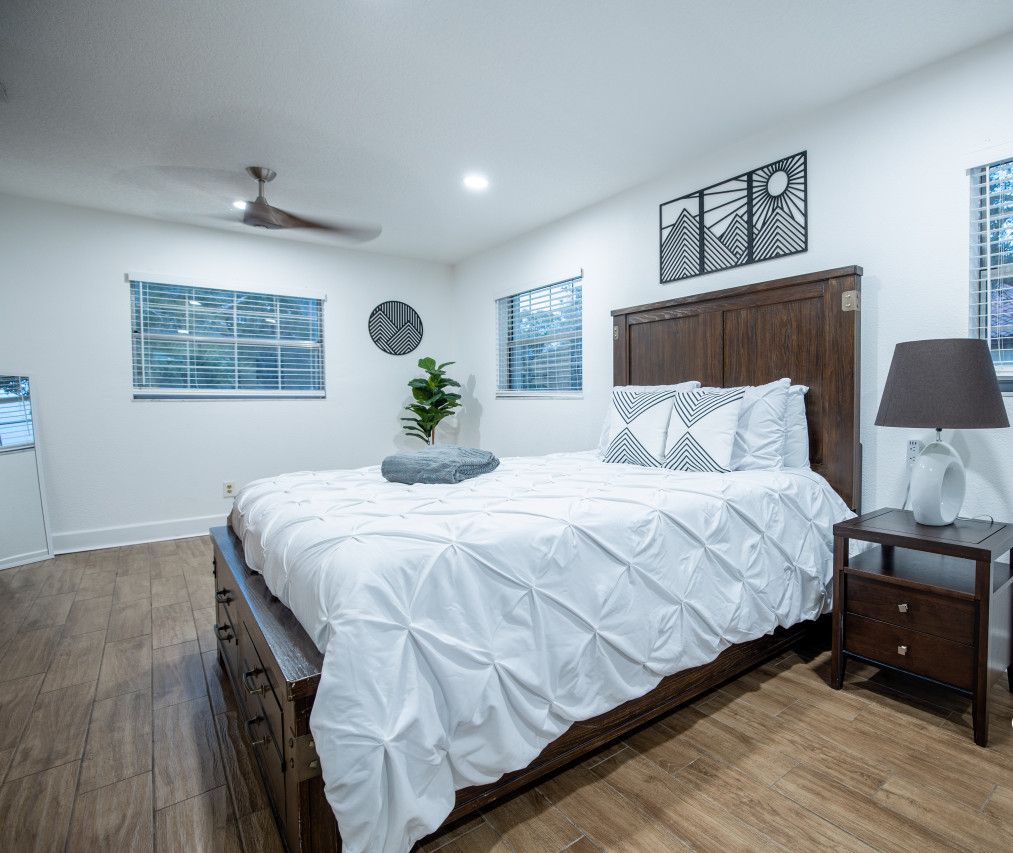 Quarto com cama, mesa de cabeceira, abajur e decoração na parede.