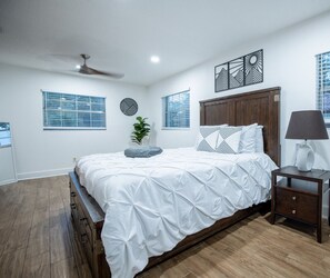 Un dormitorio con cama, mesita de noche, lámpara y decoración mural.