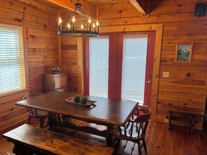 A wooden interior with a dining table, chairs, a chandelier, and a kitchen area. - 3 Bedroom + 3.5 Bath Beautiful Log Cabin with Fireplace + Stunning Mountain Views! (Mars Hill)