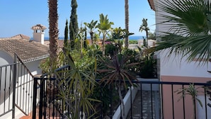 Une cour intérieure agrémentée de palmiers, un escalier et une vue sur la mer.