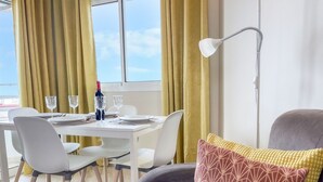 A dining area with a table set for two, two wine glasses, a bottle, and a white table lamp. - Club Maritimo Front line Beach Apartments (Fuengirola)