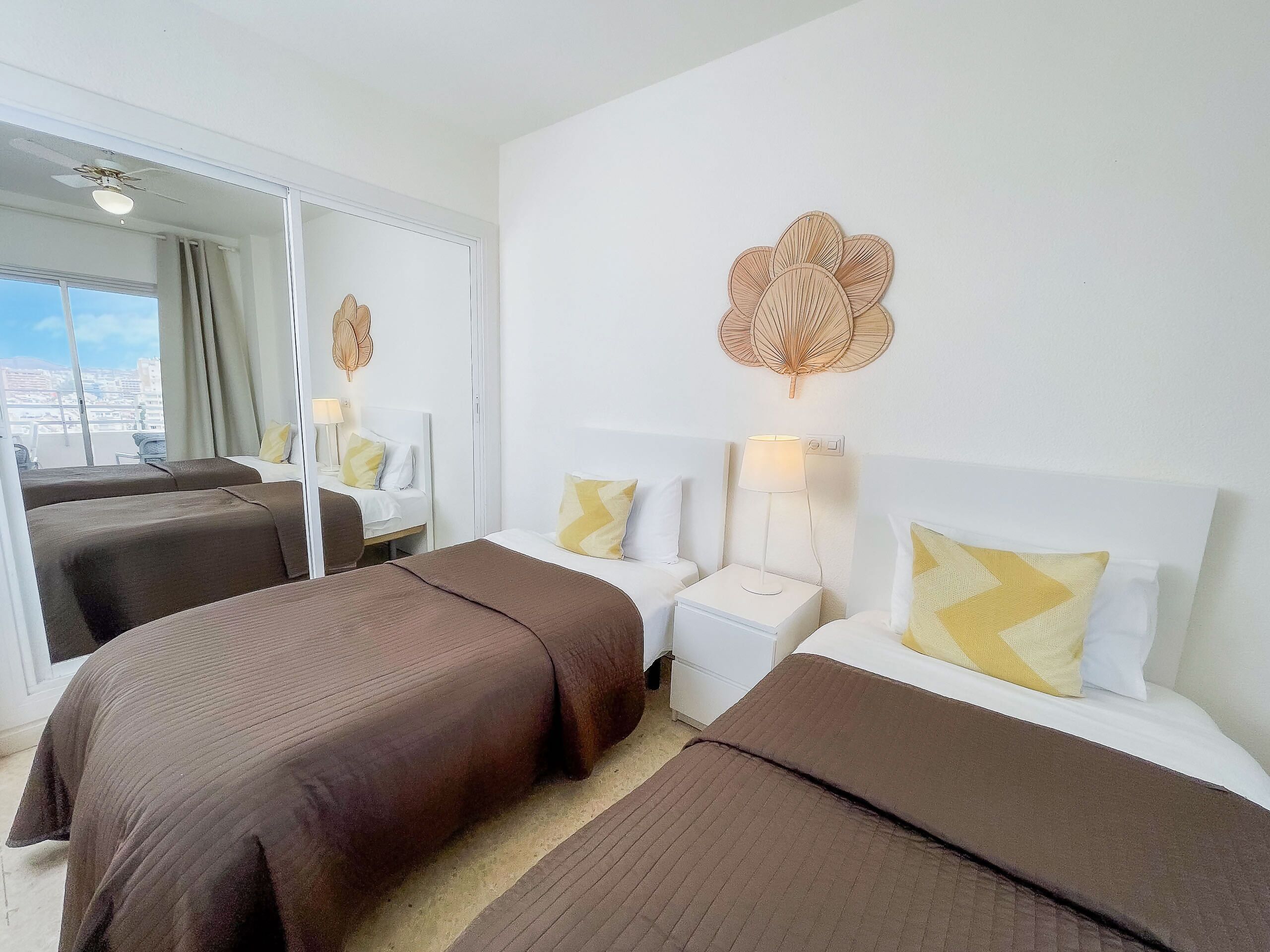 A hotel room with two beds, a large window, and a view of the city.