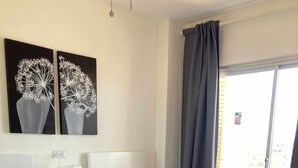 Hotellihuone, jossa on kaksi sänkyä, yöpöytä, lamppu ja ikkuna, jossa on verhot.