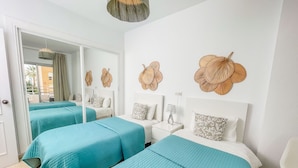A hotel room with two beds, a white nightstand, a mirror, and decorative wall art.