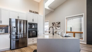 Una cocina moderna con electrodomésticos de acero inoxidable, una isla central y un cartel con la leyenda 'IMAGINE'.