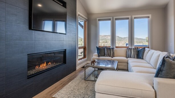 Una sala de estar moderna con chimenea, un sofá grande y vistas a las montañas.