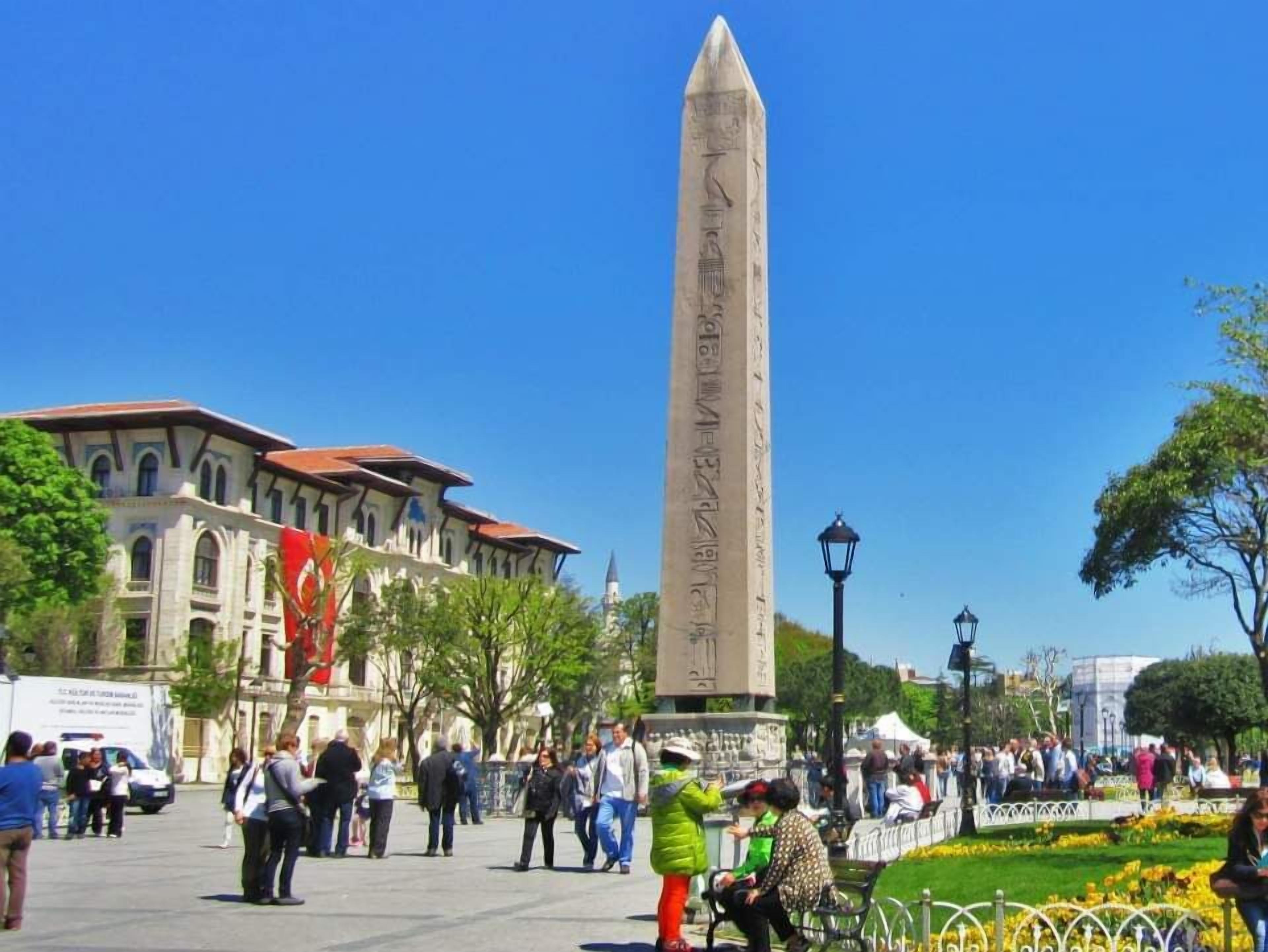Un grand obélisque, monument situé sur une place publique, entouré de personnes.