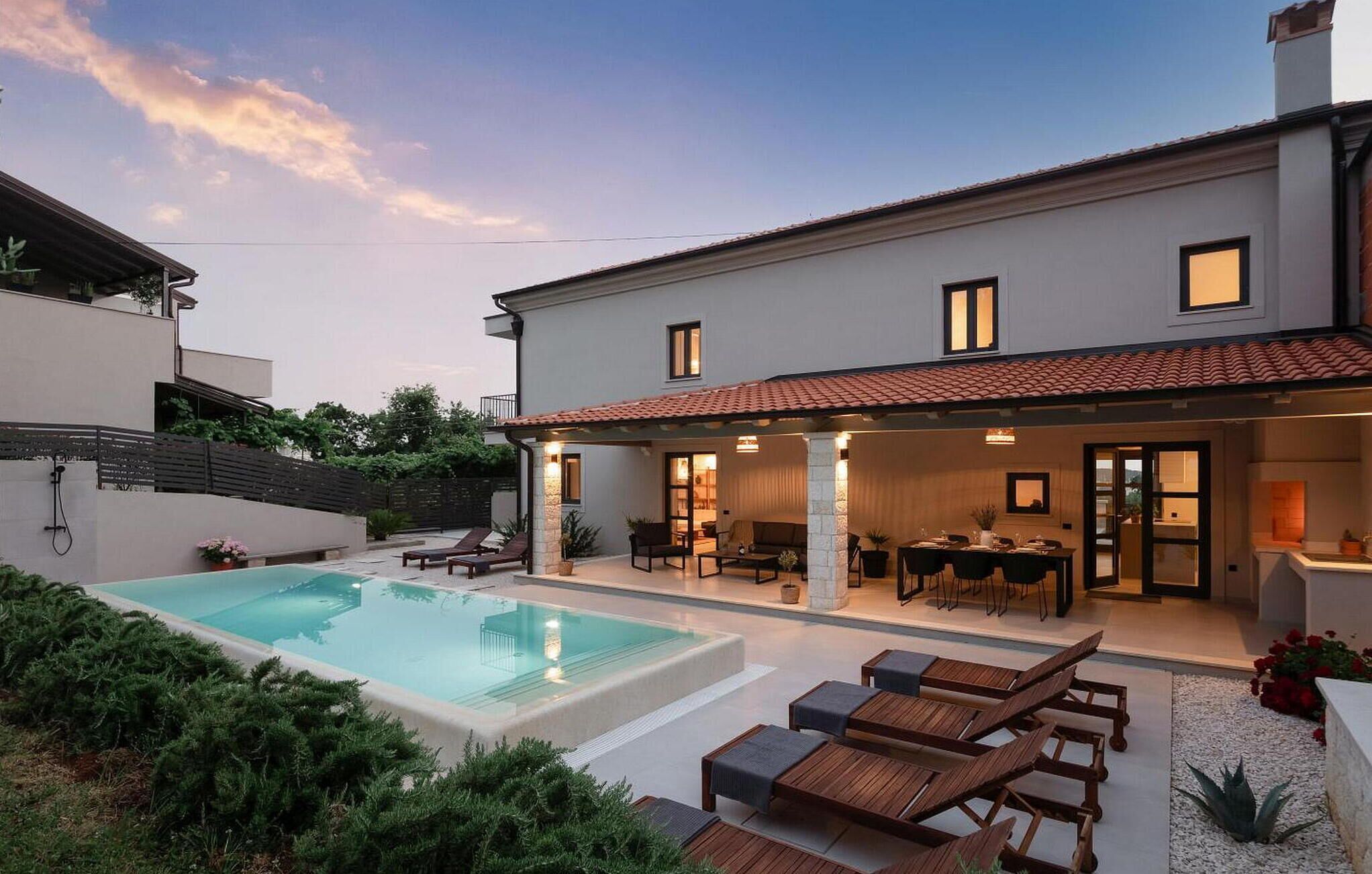 A modern two-story house with a swimming pool, outdoor seating, and a covered patio area.