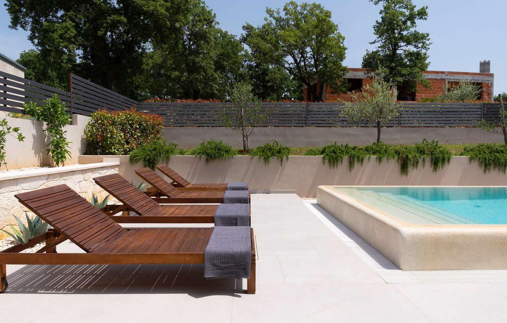 Area piscina con lettini in legno e vasca idromassaggio.