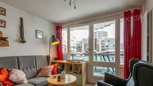 A modern living room with a grey sofa, a black armchair, a wooden coffee table, and a view of a snowy mountain through large windows. - Cozy 3-Room Ski-In Apartment for 6 in La Daille, Val d'Isère with Balcony and Parking (Val-d'Isère)