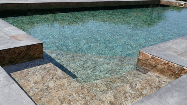 A clear pool with a stone border.