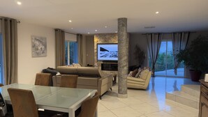 A modern living room with a sofa, TV, and dining area.