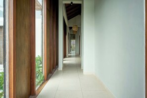 A long, narrow hallway with wooden columns and a tiled floor. - Luna Ola Villa Berawa (Canggu)