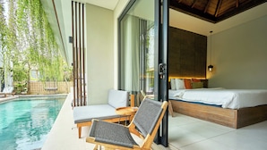 Une chambre moderne avec un grand lit, un canapé et un espace près de la piscine comprenant deux chaises longues.