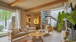 Un vaste espace de vie comprenant un canapé, des fauteuils, une table basse et un escalier menant à l’étage supérieur.
