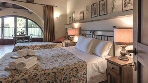 A hotel room with two beds, a wooden headboard, a nightstand with a lamp, and a window with curtains. - ONE-ROOM APARTMENTS 8 COLLE VAL D’ELSA  (Casole d'Elsa)