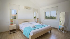 Ein Schlafzimmer mit Bett, Nachttischen, einem Spiegel und einem Fenster.