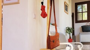A hallway with a coat rack, a bench, a potted plant, and a framed picture on the wall.