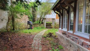 A stone pathway leading to a rustic building with a brick exterior and large windows.