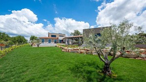 A modern house with a well-maintained lawn and a stone retaining wall.