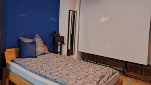 Une chambre à coucher comprenant un lit, une commode, un miroir et un luminaire suspendu.