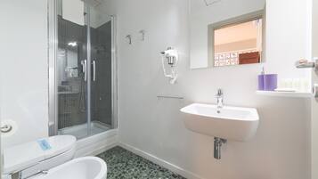 Une salle de bain équipée d’une douche, de toilettes, d’un bidet et d’un lavabo.