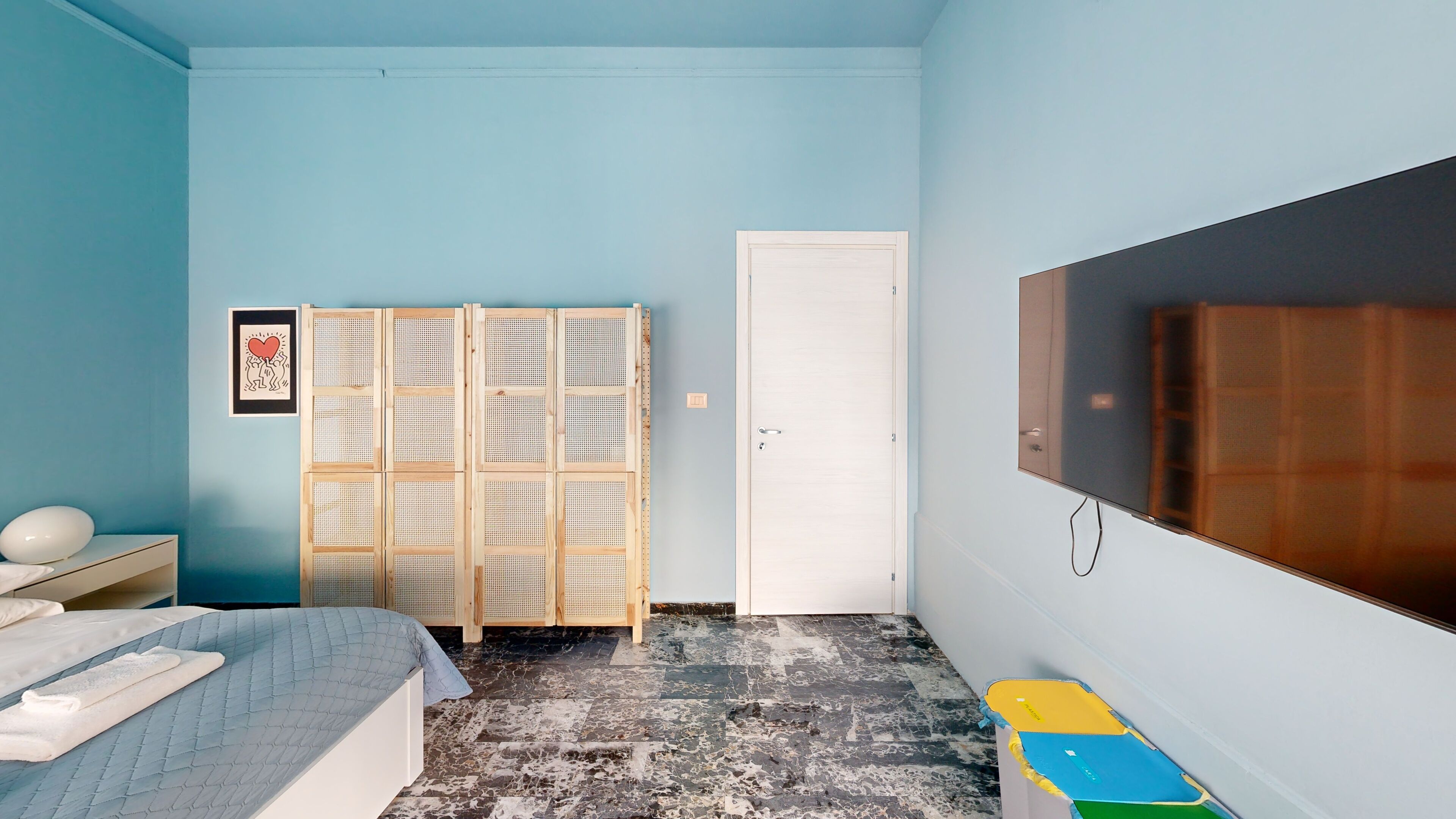 A bedroom with a bed, a TV, a wardrobe, and a door.