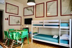 Camera con letto a castello, una scrivania, sedie e mappe incorniciate alle pareti.