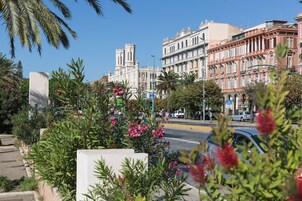 Una strada con edifici, una palma e un'auto.