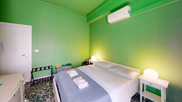 A room with a bed, bedside tables, a nightstand, a mirror, and an air conditioning unit. - Guest House Sonnino 37 Cagliari (Cagliari)