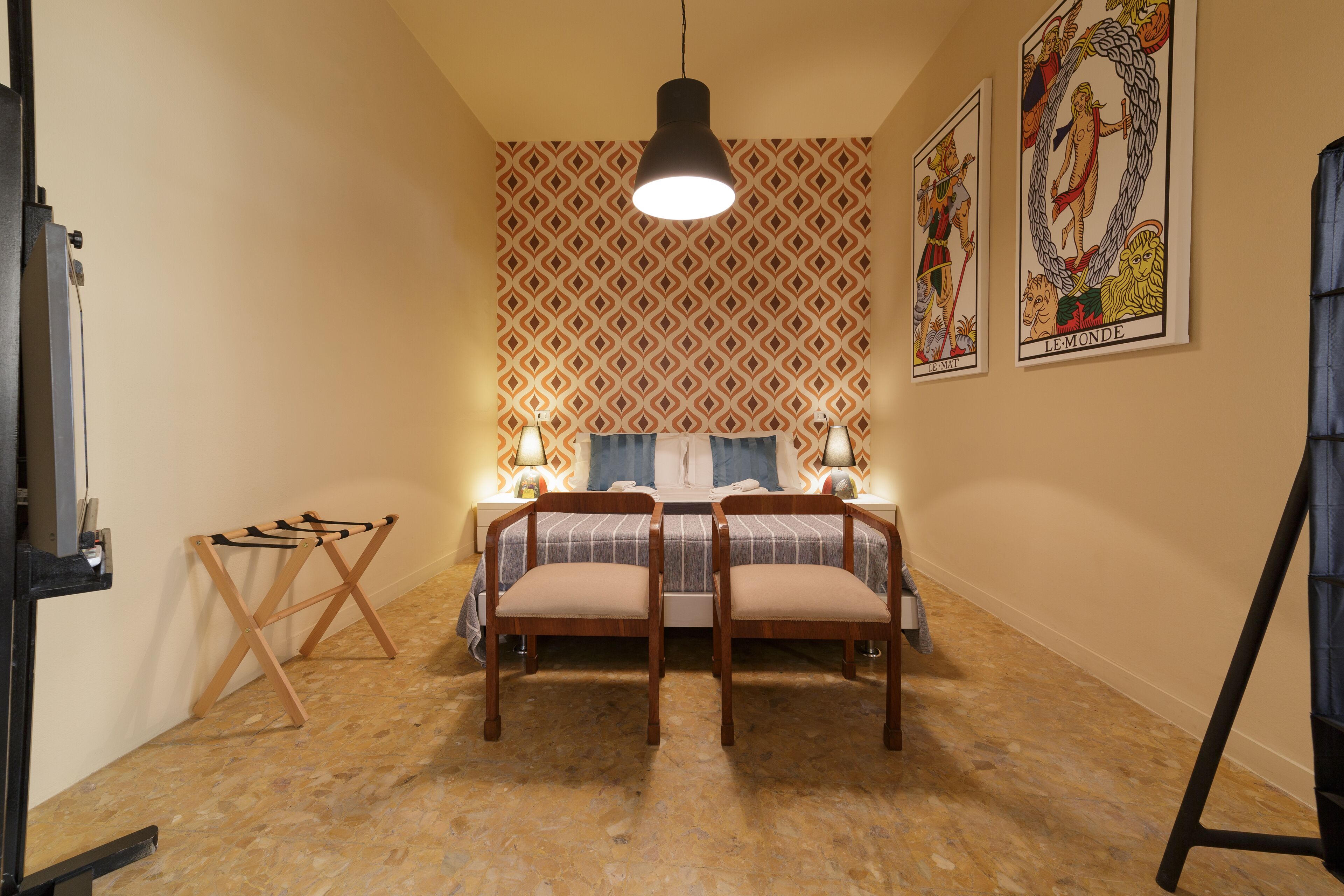 Ein Schlafzimmer mit einem Bett, zwei Stühlen, einer Stehlampe und rahmigem Wandpapier.