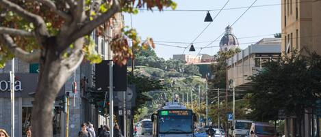 A street scene with a bus, pedestrians, and parked cars.