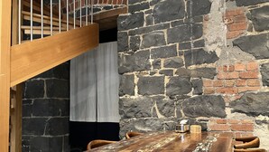 Ein rustikaler Essbereich mit Holztisch und -stühlen, einer Steinwand und einer Treppe.