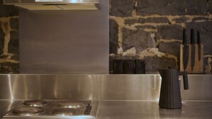 Eine Küche mit einem Edelstahlherd, einer schwarzen Kaffeemaschine und einer Steinwand im Hintergrund.