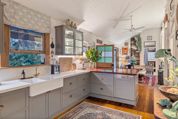 A spacious kitchen with a large island, built-in cabinets, and a view of the garden.