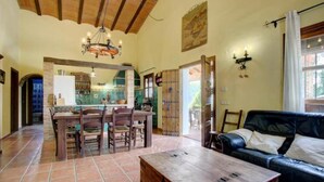 Amplia sala de estar con una mesa de comedor, sillas, un sof á de cuero y una mesa de centro de madera.