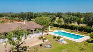 A villa with a swimming pool, surrounded by greenery and trees.