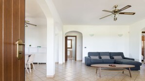A spacious living area with a dark blue sofa, a wooden coffee table, and a ceiling fan.