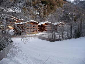 A snow-covered lodge with a wooden exterior, surrounded by trees and a snowy landscape.