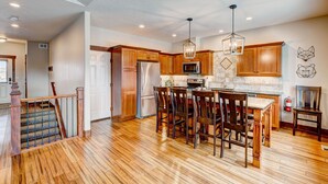 A spacious kitchen with wooden cabinets, a central island with bar stools, and a modern pendant light. - Mountain Lake View - Hot tub/Fireplace! (Estes Park)