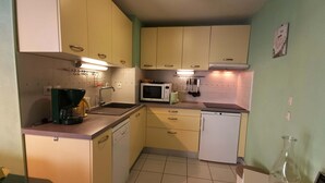 A compact kitchen with a coffee maker, microwave, and dishwasher. - Cozy 2BR Cabin Apartment with Balcony, Near Aquatic Center, Sleeps 6, No Pets (Les Adrets-Prapoutel)