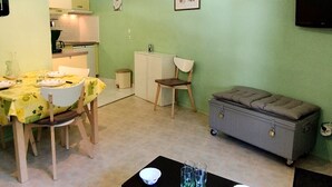 A compact living space with a dining area, kitchenette, and a grey chest of drawers. - Cozy 2BR Cabin Apartment with Balcony, Near Aquatic Center, Sleeps 6, No Pets (Les Adrets-Prapoutel)
