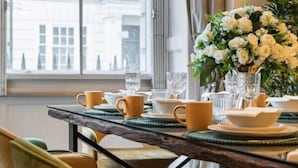 Une table à manger agrémentée de chaises jaunes, d’un vase de fleurs blanches et de verres transparents.